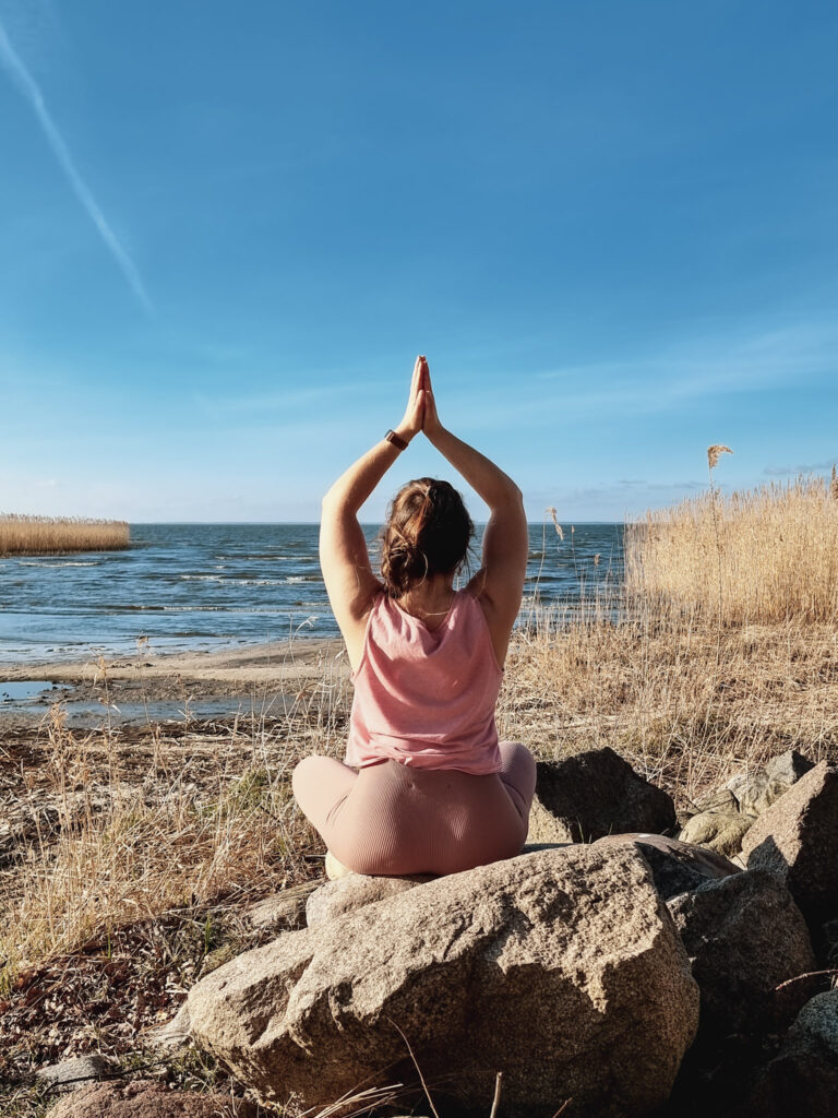 Frau in Yogapose am Strand
